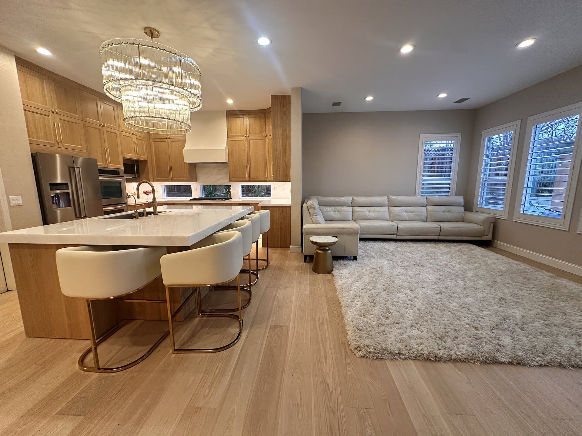 Remodeled kitchen with white oak cabinetry, stone waterfall island, and chandelier